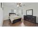 Bright bedroom featuring wood floors, ceiling fan, a large dresser and shuttered windows at 4615 W Corral Rd, Laveen, AZ 85339