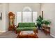 Living room with green sofa, wooden accents, and large window at 1231 N Layman St, Gilbert, AZ 85233