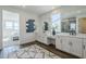 Bright bathroom featuring dual vanities with white countertops, white cabinets, and wood-look tile at 17219 W Vacaville St, Surprise, AZ 85388