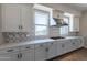 Modern kitchen with white cabinets, gas cooktop and patterned backsplash at 17380 W Carlisle Dr, Surprise, AZ 85388