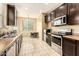 Modern kitchen features dark wood cabinets, stainless steel appliances, and tile flooring at 1940 N 78Th Gln, Phoenix, AZ 85035