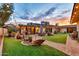 Spacious backyard with lush lawn, patio seating, and charming string lights at dusk at 4022 E Stanford Dr, Phoenix, AZ 85018