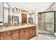 Bathroom vanity featuring double mirrors and a stone countertop, plus glass door shower at 4022 E Stanford Dr, Phoenix, AZ 85018