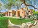 Beautiful desert landscaping surrounds this Spanish style home with a lush green lawn at 8494 E Gilded Perch Dr, Scottsdale, AZ 85255