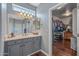 Bathroom showcasing vanity, large mirror, ample lighting, and open walk-in closet with custom shelves for easy access at 12942 W Sola Dr, Sun City West, AZ 85375