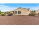 Rear view of property showcasing desert landscape, neutral stucco, and covered patio with outdoor seating at 12942 W Sola Dr, Sun City West, AZ 85375