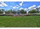 Beautiful fountain surrounded by lush green grass and colorful flowers, set against a backdrop of mature trees and blue sky at 12942 W Sola Dr, Sun City West, AZ 85375