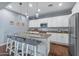 Well-lit kitchen featuring an island with bar stools, stainless steel appliances, and custom pendant lights at 12942 W Sola Dr, Sun City West, AZ 85375