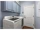 Modern laundry room with upper cabinets and a white washer and dryer set at 12942 W Sola Dr, Sun City West, AZ 85375