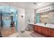 Bathroom with double vanity, large mirror, and view of bedroom at 6962 W Glenn Dr, Glendale, AZ 85303