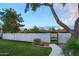 Landscaped backyard with grassy lawn, tall trees, and a white wall at 8709 E Irish Hunter Trl, Scottsdale, AZ 85258