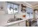 White kitchen with subway tile backsplash, stainless steel sink, and floating shelves at 10405 W Patrick Ln, Peoria, AZ 85383
