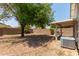 Sunny backyard with gravel, tree, and covered patio at 15306 W Eureka Trl, Surprise, AZ 85374