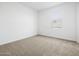 A bright bedroom with neutral carpet, white walls, and a window for natural light at 22563 W Pontiac Dr, Surprise, AZ 85387