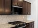 Detail of a modern kitchen with a gas cooktop, stainless steel microwave, and patterned tile backsplash at 22563 W Pontiac Dr, Surprise, AZ 85387