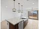 Contemporary kitchen island with stainless steel sink and faucet, modern pendant lights, and sliding glass door at 22563 W Pontiac Dr, Surprise, AZ 85387