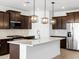 Modern kitchen with stainless steel appliances, granite countertops, dark wood cabinets, and stylish pendant lights at 22563 W Pontiac Dr, Surprise, AZ 85387