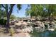 Peaceful water feature with a waterfall and pond, surrounded by lush landscaping at 2527 W Kit Carson Trl, Anthem, AZ 85086