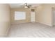 Bright living room with plush neutral carpet, large window with blinds, and a ceiling fan at 25241 W Park Ave, Buckeye, AZ 85326