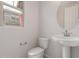 Contemporary powder room featuring a pedestal sink, round mirror and toilet in a neutral palette at 2917 N Evergreen St, Buckeye, AZ 85396