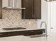 Modern kitchen featuring stainless steel appliances, gas cooktop, chevron backsplash and dark cabinetry at 4822 N 177Th Ln, Goodyear, AZ 85395