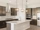 Spacious kitchen featuring a center island, pendant lights, stainless appliances, and dark cabinetry at 4822 N 177Th Ln, Goodyear, AZ 85395