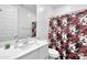 Clean bathroom with white vanity, shower, and floral shower curtain at 5932 S 26Th Ave, Phoenix, AZ 85041