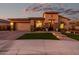 Two-story house with tan exterior, landscaped yard and a three-car garage at 21122 W Edgemont Ave, Buckeye, AZ 85396