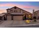 Charming two-story home featuring a three-car garage and desert landscaping at dusk at 2249 E Taxidea Way, Phoenix, AZ 85048