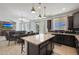 Open-concept kitchen with dark cabinets, stainless appliances, and a center island, flows seamlessly into the adjacent dining and living areas at 3446 N Mayfair St, Mesa, AZ 85213