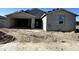 New construction gray home with attached garage and front yard with dirt and concrete driveway at 5510 W Paseo Way, Laveen, AZ 85339