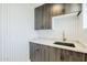 Modern laundry room features gray cabinetry, a gold faucet, quartz countertops and a unique herringbone accent wall at 8525 E Via De Los Libros --, Scottsdale, AZ 85258