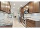 Modern kitchen with stainless steel appliances, granite countertops and wood cabinets overlooking a living room with a fireplace at 5998 N 78Th St # 116, Scottsdale, AZ 85250