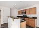 Functional kitchen features wooden cabinets, black countertops, breakfast bar, and modern appliances at 18409 W Dawn Dr, Surprise, AZ 85374