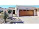 Spanish style home with landscaped front yard, featuring a wooden garage door and desert plants at 18658 E Mazatzal Cir, Rio Verde, AZ 85263