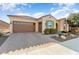 Front view of a tan house with a brown garage door and drought-tolerant landscaping at 26573 W Abraham Ln, Buckeye, AZ 85396