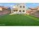 Large backyard with artificial turf and a two-story house at 37855 W Merced St, Maricopa, AZ 85138