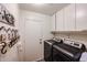 Laundry room with washer, dryer, cabinets, and hanging decor at 6352 W Campo Bello Dr, Glendale, AZ 85308