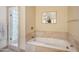 Bright bathroom features a soaking tub with travertine surround and glass block shower at 6411 S River Dr # 10, Tempe, AZ 85283