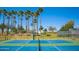 Well-maintained tennis court with palm trees creating a resort-like atmosphere under a bright blue sky at 18147 W Desert View Ln, Goodyear, AZ 85338