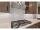 Gas cooktop with stainless steel range hood and white subway tile backsplash at 21259 E Sparrow Dr, Queen Creek, AZ 85142