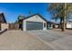 Ranch style home with gray garage door and landscaped yard at 6934 W Mclellan Rd, Glendale, AZ 85303