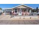 Tan mobile home with covered porch, red chairs, and landscaped yard at 8865 E Baseline Rd # 1106, Mesa, AZ 85209