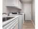 Laundry room area with washing machine, sink, cabinets and door to the exterior at 10417 E Champagne Dr, Sun Lakes, AZ 85248
