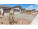 A three car garage with paver driveway, rock landscaping, and gray exterior paint at 12358 W Marguerite Ave, Avondale, AZ 85323