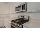 Close-up of stainless steel microwave and range with white cabinets and light countertop at 12358 W Marguerite Ave, Avondale, AZ 85323