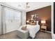Bright bedroom with a double bed, brown accent wall, and window coverings at 38130 W Bello Ln, Maricopa, AZ 85138