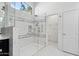 Luxurious bathroom featuring a spacious glass shower, marble tile surround, and an arched window for natural light at 5403 E Cannon Dr, Paradise Valley, AZ 85253