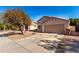 House exterior, showing a tan stucco house with a two-car garage and a tree in the front yard at 13859 N 91St Ln, Peoria, AZ 85381