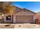 Front view of a tan house with a two-car garage and mature tree in front at 13859 N 91St Ln, Peoria, AZ 85381